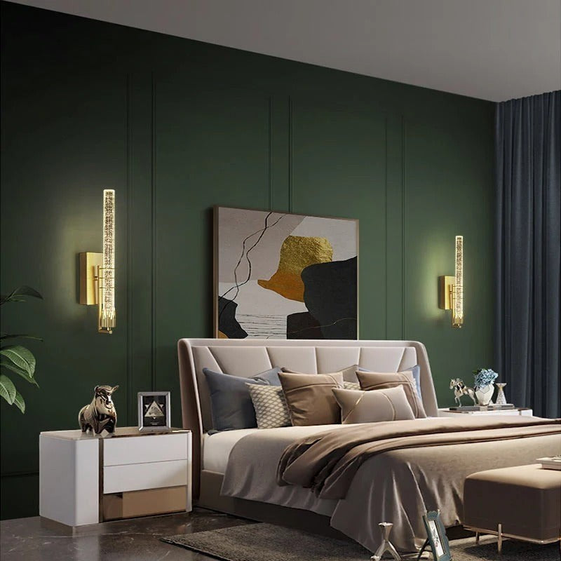 Applique murale Dimoree moderne en cristal doré installée de chaque côté d'un lit dans une chambre au mur vert foncé