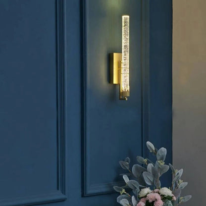 Applique murale Dimoree moderne en cristal doré fixée sur un mur bleu profond pour un éclairage élégant