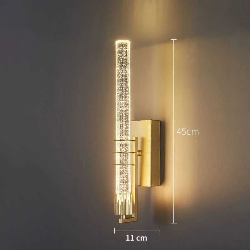 Applique murale Dimoree moderne en cristal cylindrique avec finition dorée diffusant une lumière chaude dans un salon