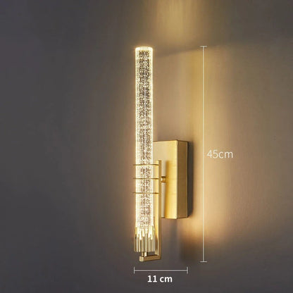 Applique murale Dimoree moderne en cristal cylindrique avec finition dorée diffusant une lumière chaude dans un salon