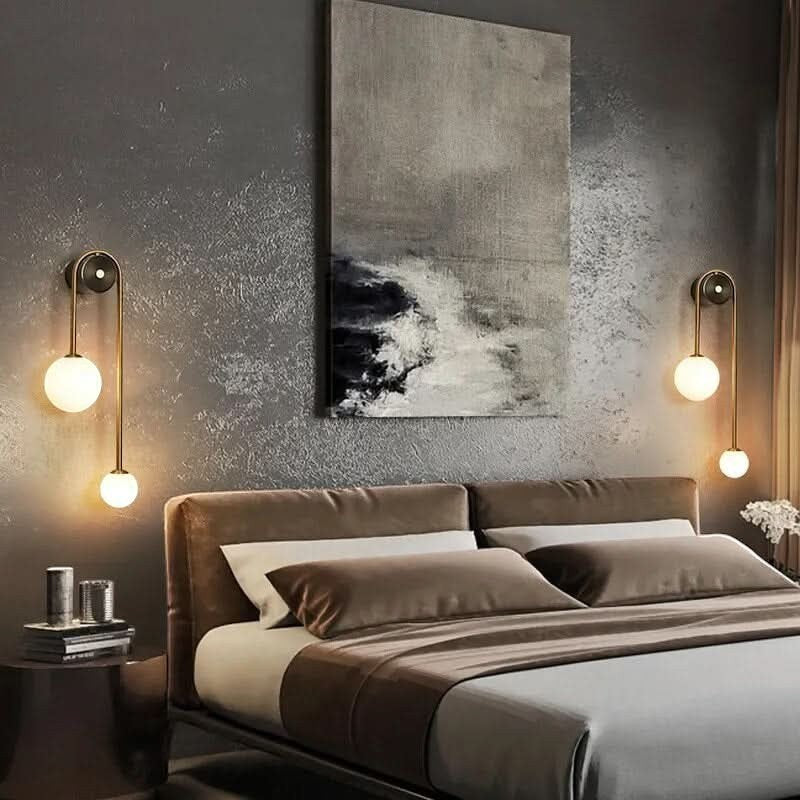 Applique murale Dimoree design à deux sphères lumineuses en métal doré installée dans une chambre moderne