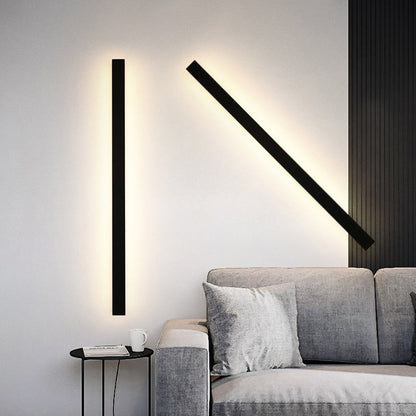 Applique murale Dimoree LED noire au design minimaliste et linéaire installée sur un mur blanc au-dessus d'un canapé