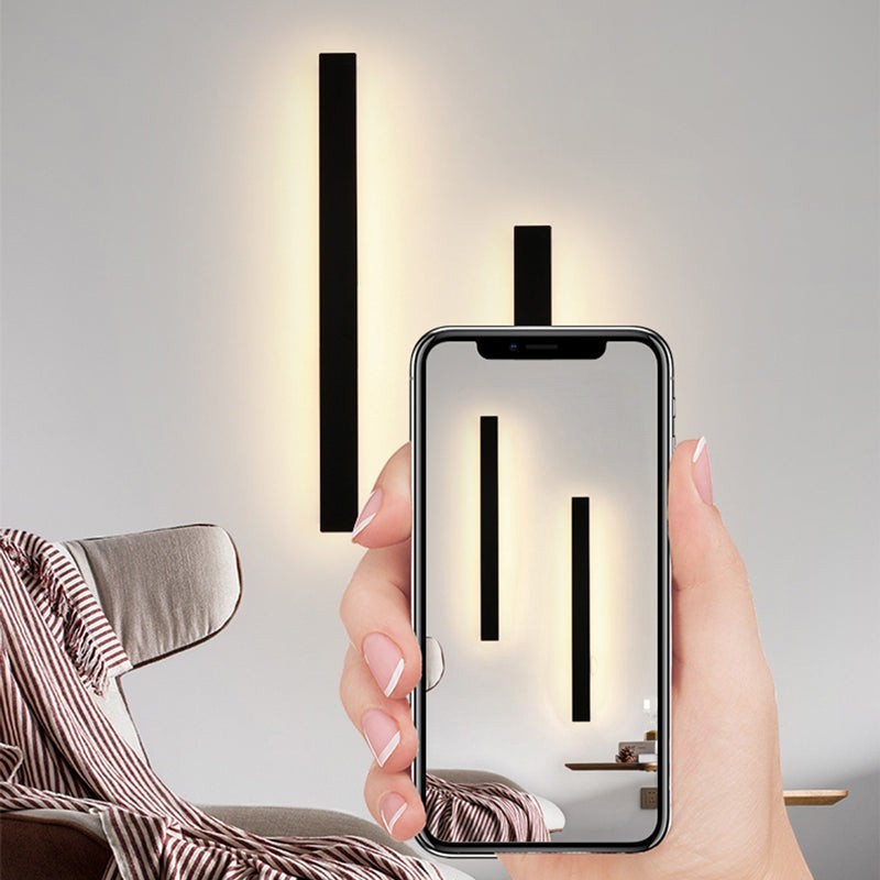 Applique murale Dimoree minimaliste noire en métal avec éclairage LED diffusant une lumière douce sur un mur intérieur
