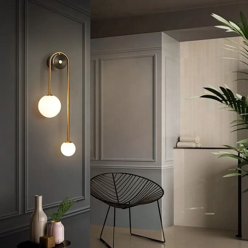 Applique murale Dimoree moderne à deux sphères en verre opalin et métal doré sur un mur gris élégant