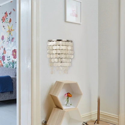 Applique murale Dimoree en nacre blanche avec pampilles circulaires suspendues dans un salon moderne