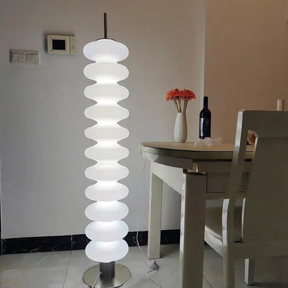 Lampadaire design Dimoree en acrylique blanc avec structure empilée diffusant une lumière douce dans un salon