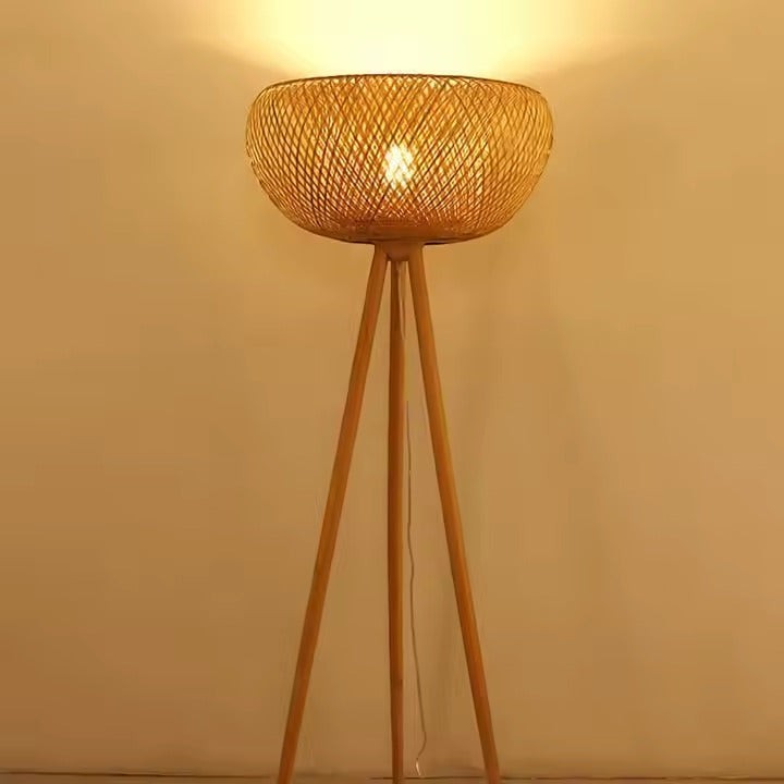Lampadaire trépied Dimoree en bambou tressé naturel diffusant une lumière douce pour une ambiance bohème chic.