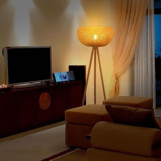 Lampadaire trépied Dimoree en bambou tressé diffusant une lumière douce et chaleureuse dans un salon bohème.