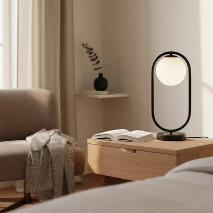 Lampe à poser LED Dimoree au design moderne avec globe en verre blanc et structure noire sur une table de chevet en bois
