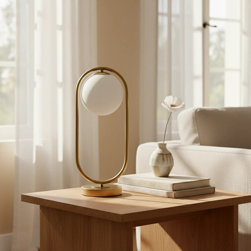 Lampe à poser LED Dimoree avec globe en verre blanc et structure ovale en métal doré sur une table en bois