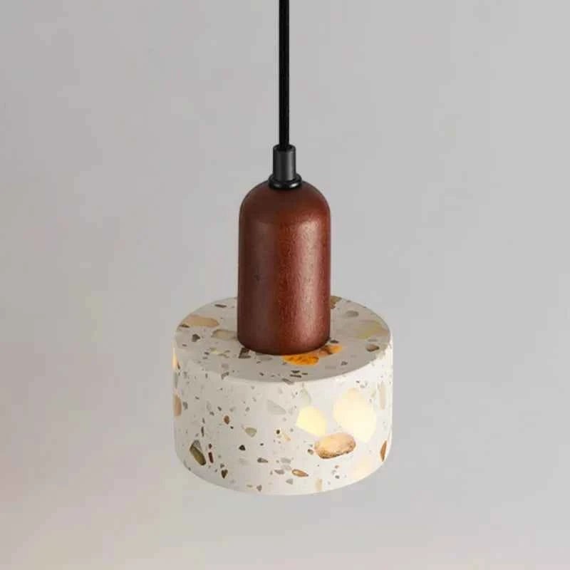 Suspension lumineuse Dimoree de style Wabi Sabi avec abat-jour cylindrique en terrazzo et support en bois sombre.