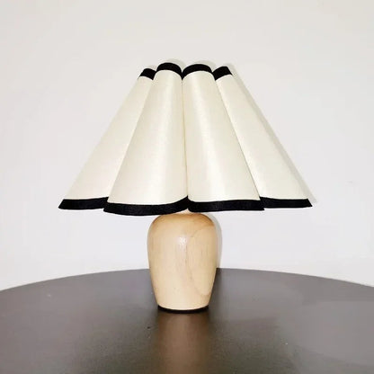 Lampe de table Dimoree avec base en bois clair et abat-jour plissé crème à bordures noires pour une ambiance cosy