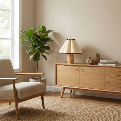 Lampe de table Dimoree avec base en bois clair et abat-jour plissé crème à liseré noir sur un buffet en bois