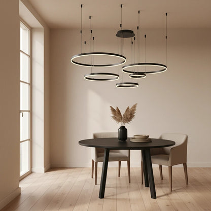 Lustre suspendu Dimoree à anneaux LED noirs modernes au-dessus d'une table de salle à manger ronde en bois noir