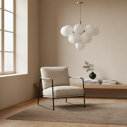 Lustre Dimoree en verre soufflé blanc avec structure dorée suspendu au-dessus d'un fauteuil moderne dans un salon beige.