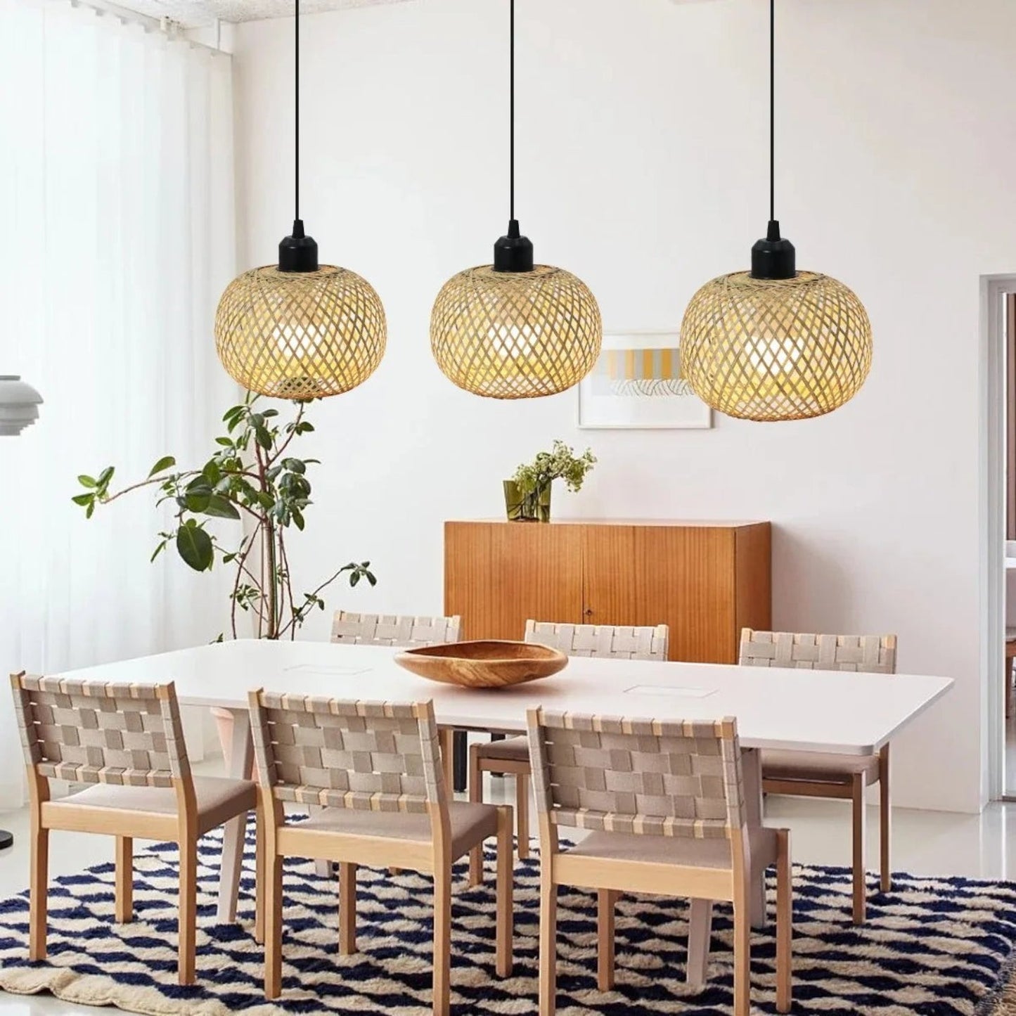 Trois suspensions Dimoree en bambou tissé naturel au-dessus d'une table à manger dans un intérieur moderne et épuré