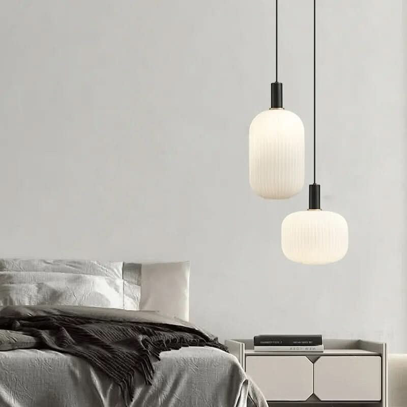 Suspension lumineuse moderne Dimoree en verre dépoli nervuré avec structure en métal noir mat au-dessus d'un lit.