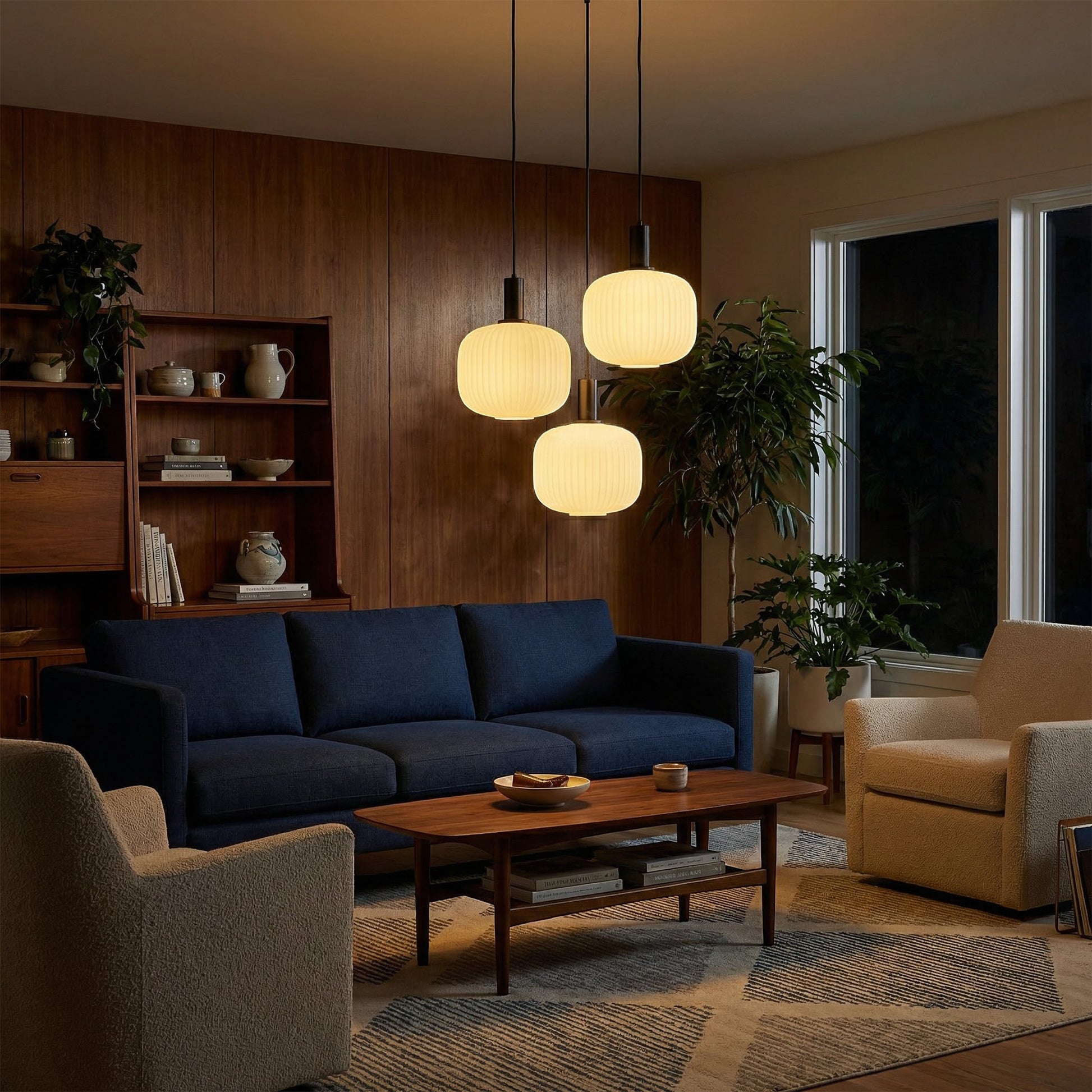 Suspension lumineuse Dimoree à trois globes en verre dépoli nervuré avec structure en métal noir dans un salon moderne.