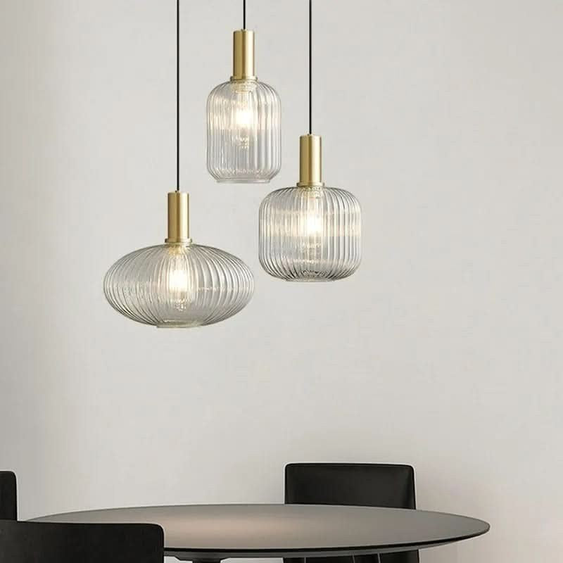 Suspension Dimoree moderne avec trois lampes en verre nervuré et structure en métal doré brossé au-dessus d'une table