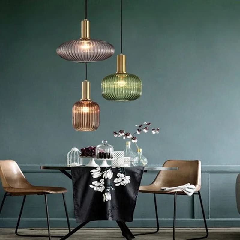 Suspension lumineuse Dimoree en verre nervuré coloré et métal doré brossé au-dessus d'une table de salle à manger