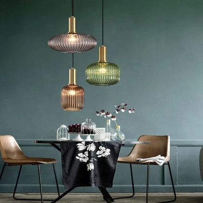 Suspension lumineuse Dimoree en verre nervuré coloré et métal doré brossé au-dessus d'une table de salle à manger