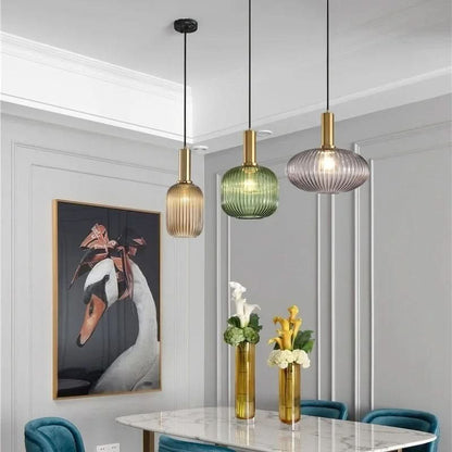 Suspension lumineuse Dimoree en verre nervuré coloré avec structure en métal doré pour salle à manger moderne.