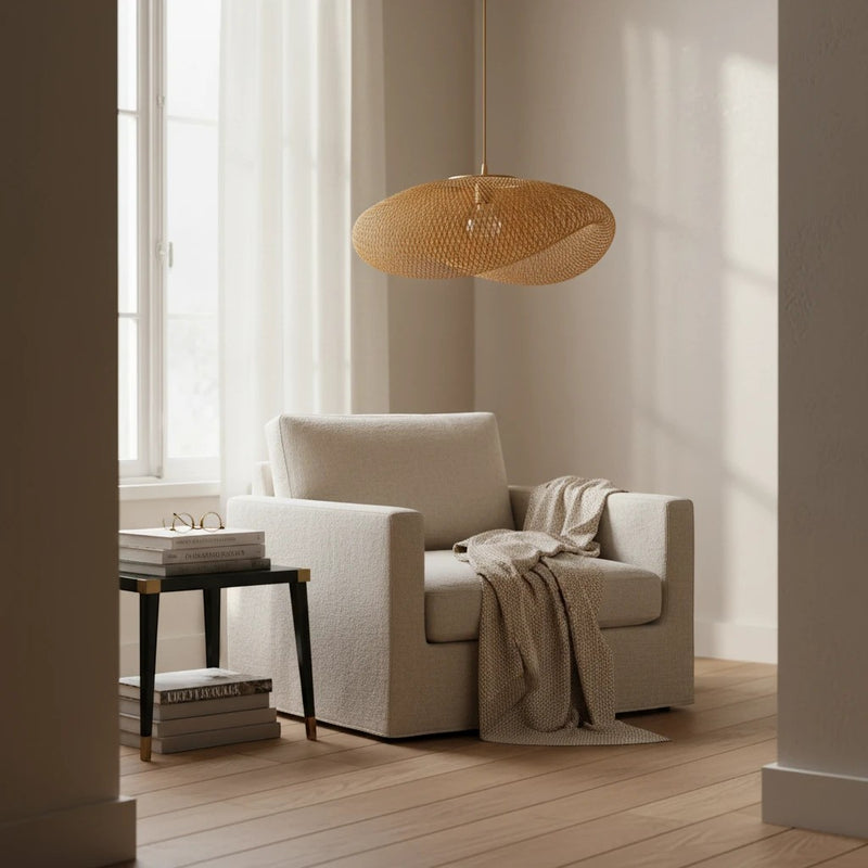Suspension Dimoree en rotin naturel tressé au design organique, installée au-dessus d'un fauteuil beige dans un salon.