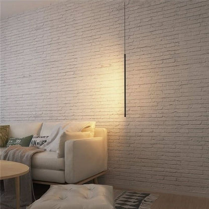 Suspension lumineuse tubulaire noire Dimoree au design minimaliste moderne devant un mur en briques blanches