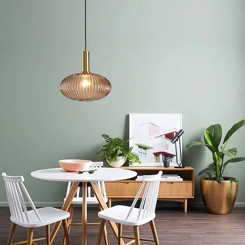 Suspension Dimoree en verre fumé nervuré et métal doré brossé au-dessus d'une table de salle à manger moderne.